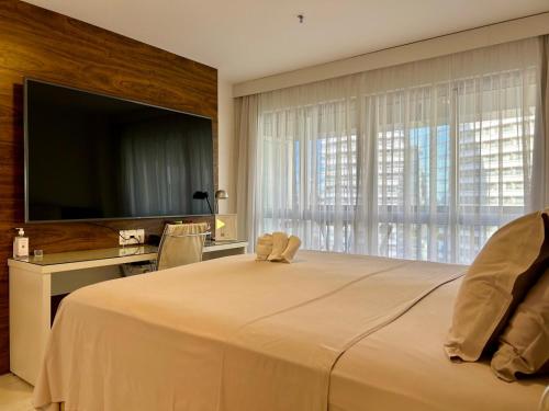 een slaapkamer met een groot bed, een bureau en een televisie bij Charme de Paris Fusion in Brasilia