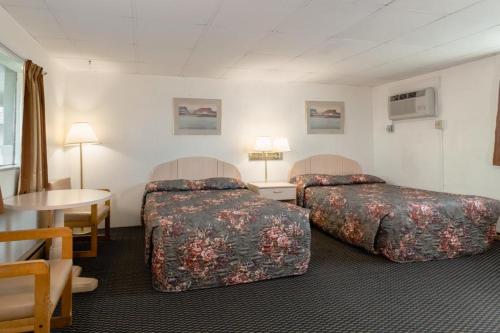 a hotel room with two beds and a table at DuBois Manor Motel in DuBois