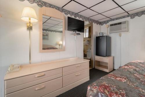 a bedroom with a bed and a dresser with a television at DuBois Manor Motel in DuBois