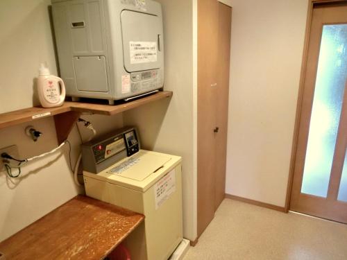 a room with a microwave on top of a refrigerator at Kencha Rumah in Hachijo