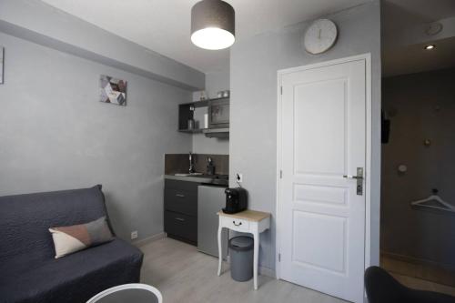 un salon avec un canapé et une horloge au mur dans l'établissement Studio cosy à Clermont-Ferrand 25 m² proche transport, à Clermont-Ferrand