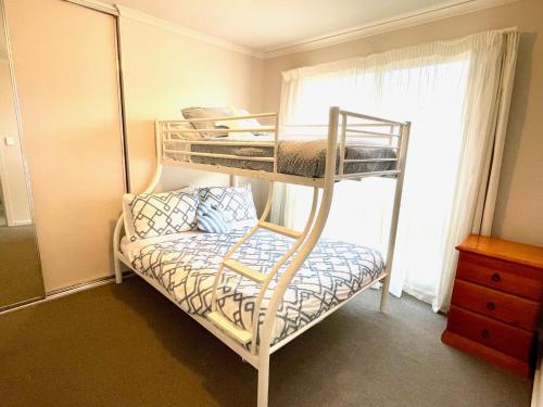 a bedroom with bunk beds with a chair and a window at Sand & Salt in Kingscote