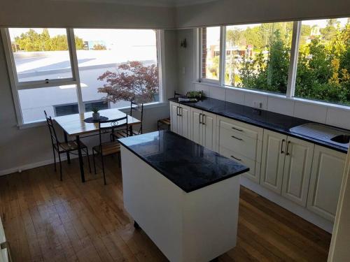 a kitchen with a counter and a table and windows at Handy Location - 3brd home! in Timaru