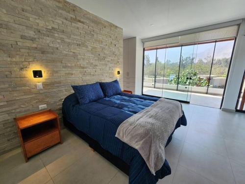a bedroom with a blue bed and a brick wall at Casa de campo de estreno en Cieneguilla, Lima-Perú in Cieneguilla