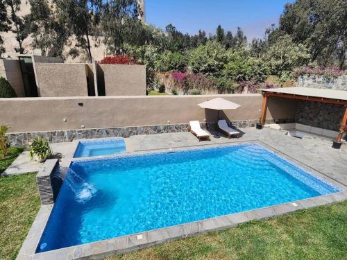 a large blue swimming pool with two chairs and a table at Casa de campo de estreno en Cieneguilla, Lima-Perú in Cieneguilla