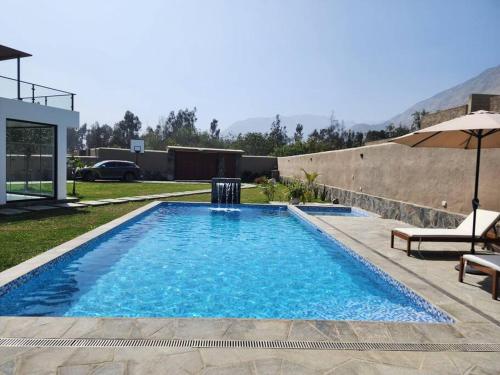 a swimming pool in a yard next to a house at Casa de campo de estreno en Cieneguilla, Lima-Perú in Cieneguilla
