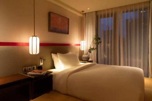 ホーチミン・シティにあるSuzu Saigon - A Boutique Hotelの白いベッドと机と窓のある寝室