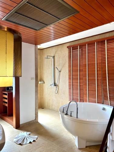 a bathroom with a large tub in a room at The Sarann, Koh Samui - Suites & Villas in Chaweng Noi Beach