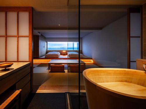 a bathroom with a tub and a bedroom at Awaji International Hotel The Sunplaza in Sumoto