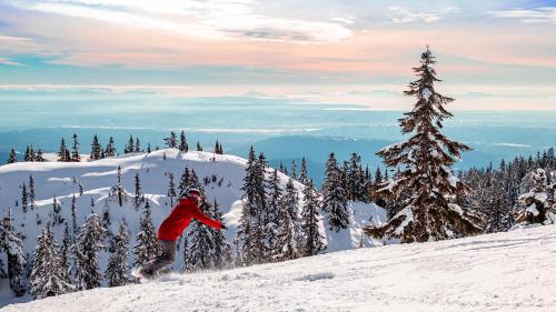 a person riding a snowboard down a snow covered slope at Seymour Private Bedroom, Ensuite Bathroom with Shared Pool, Hot Tub with Views in North Vancouver