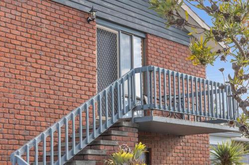 a brick building with a staircase next to a window at Harbour Lights - townside with a pool in Merimbula