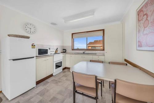 a kitchen with a large white table and chairs at Harbour Lights - townside with a pool in Merimbula