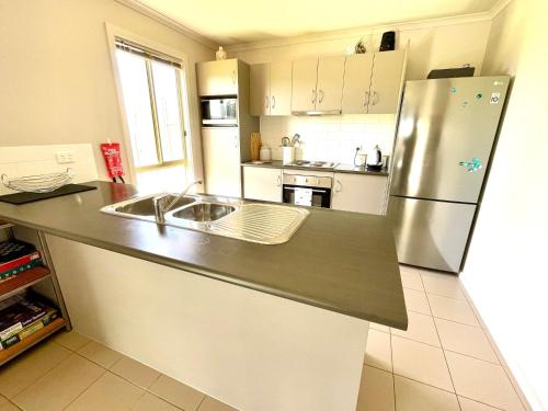 a kitchen with a stainless steel refrigerator and a sink at Sand & Salt in Kingscote
