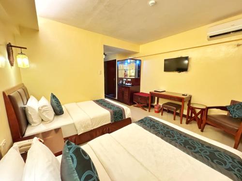 a hotel room with two beds and a television at Golden Phoenix Hotel Boracay in Boracay