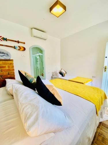 a bedroom with two beds with yellow and white pillows at Pousada Petit Refuge in Juquei