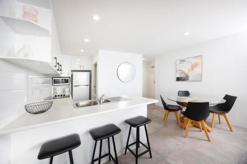 a white kitchen with a table and chairs at Ebbtide unit 17 in Forster