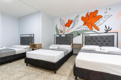 two beds in a room with a mural on the wall at Hotel Guayacanes 70 in Medellín