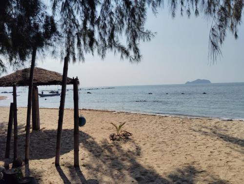 a beach with a straw umbrella and the ocean at Koh Phaluai beach cottage in Koh Phaluai