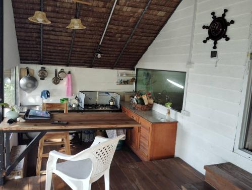 a kitchen with a wooden table and a television in a room at Koh Phaluai beach cottage in Koh Phaluai