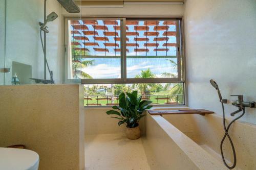 a bathroom with a tub and a window with a plant at Camfusion House in Hoi An