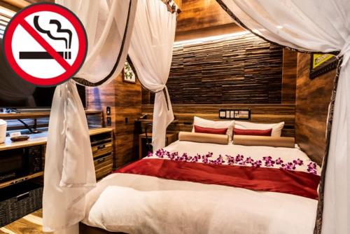 a bedroom with a bed with a no smoking sign at Petit Bali Forest Shinjuku Sanchōme in Tokyo