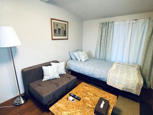 Yokohama Ivy 103 - 横浜アイビー清水ヶ丘103 - في يوكوهاما: غرفة نوم صغيرة بها سرير وأريكة