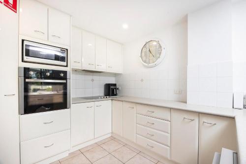 a kitchen with white cabinets and a clock on the wall at Mirage Unit 101 in Tuncurry