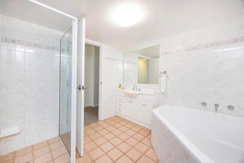 a white bathroom with a tub and a sink at Mirage Unit 101 in Tuncurry