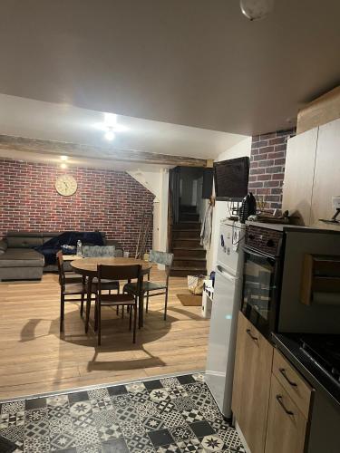 une cuisine et une salle à manger avec une table et un mur en briques dans l'établissement Petite maison de village, à Saint-Jean-sur-Mayenne