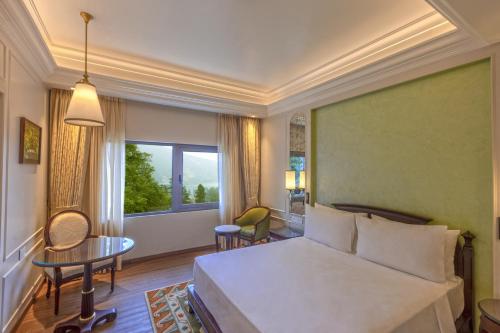 a bedroom with a bed and a table and a window at Namah Nainital, a member of Radisson Individuals Retreats in Nainital