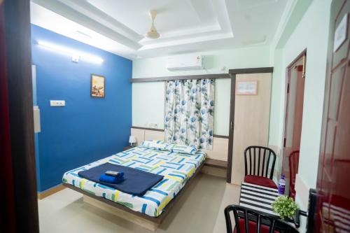 a blue bedroom with a bed and a chair at Sree Theja Residency in Anantapur