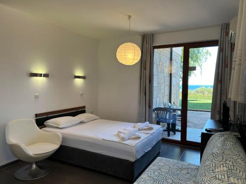 a bedroom with a bed and a chair and a window at View Apartments in Sozopol