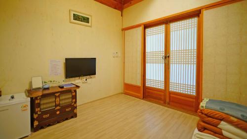 a living room with a television and sliding glass doors at Sarangroo in Jeonju