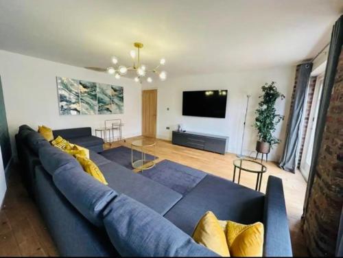un soggiorno con un divano blu e una TV a schermo piatto di Barn near York with hot tub - Perfect for Groups and Families a York