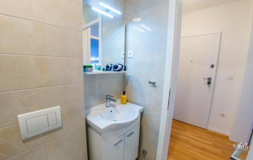 a white bathroom with a sink and a mirror at Apartman Mary in Široki Brijeg