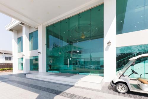 a glass building with a small car parked outside at River Hotel - The Outstanding Venues Nakhon Pathom in Ban Hua Na Pa