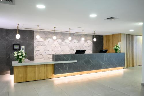 a lobby with a reception counter with flowers on it at Kinar Galilee in Kinar
