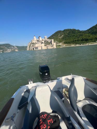 a boat on the water with a castle in the background at Relax Residence in Golubac