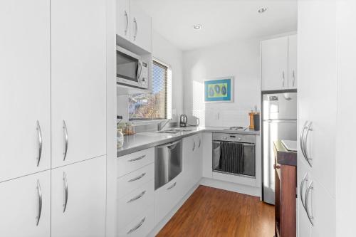 a kitchen with white cabinets and stainless steel appliances at Gather Taupo - Lakeview - Spa Pool in Taupo