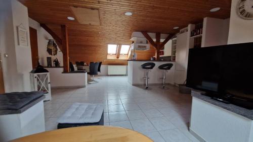 a large room with a bar with stools and a tv at Ferienwohnung Schwarz in Gasseldorf