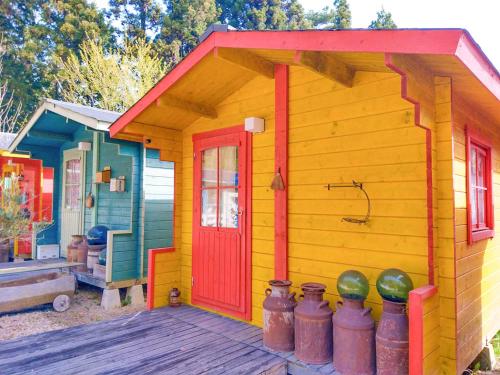 a small house with a red door on a deck at 星逢える宿ー森のコテージ気仙沼 in Kesennuma