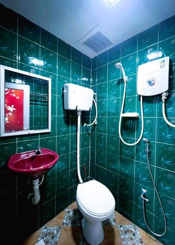a green tiled bathroom with a toilet and a sink at Damansara Damai Hotel- DD in Petaling Jaya