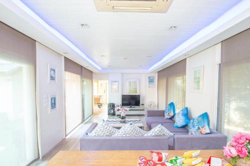 ein Wohnzimmer mit zwei lila Sofas und einem TV in der Unterkunft Sea blue pool villa in Bang Lamung