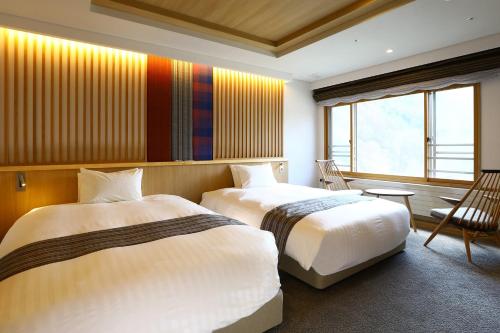 a hotel room with two beds and a window at Saito Hotel in Ueda