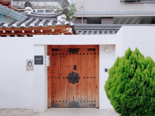 a wooden door of a house with a hedge at Cheongryang-Anchae 2BR 2BA Hanok Spa Free Parking in Seoul