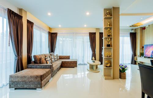 a living room with a couch and a tv at "Smooth as Silk" Gorgeous 3-Bedroom Pool Villa, Just a Stone's Throw from the Beach! in Ban Khlong Haeng