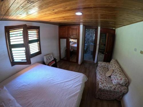 a bedroom with a white bed and two chairs at Hospedaje Villa Valencia en Los Patos in Los Patos