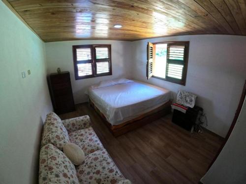 a bedroom with a bed and a couch and windows at Hospedaje Villa Valencia en Los Patos in Los Patos