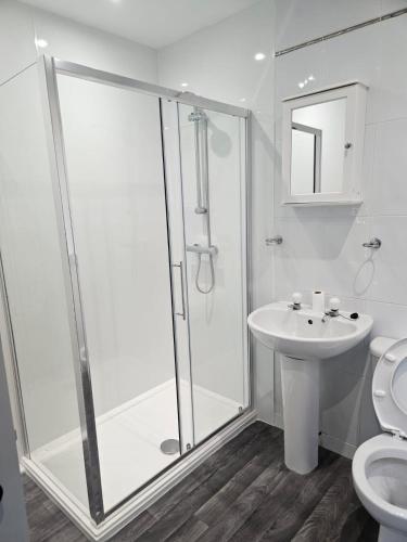 a white bathroom with a shower and a sink at LANGLEY HOUSE Free Parking central LOCATION 5 bed all double with smart TV 3 BATHROOMS Loved by TRADES teams ideal for LONG STAYS contact langley cottages and apartments in Dundee