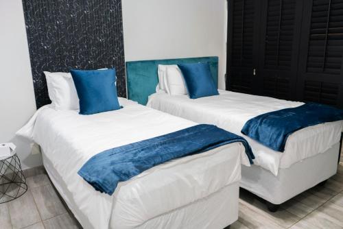 two beds with blue pillows in a room at See You There Accommodation in Centurion